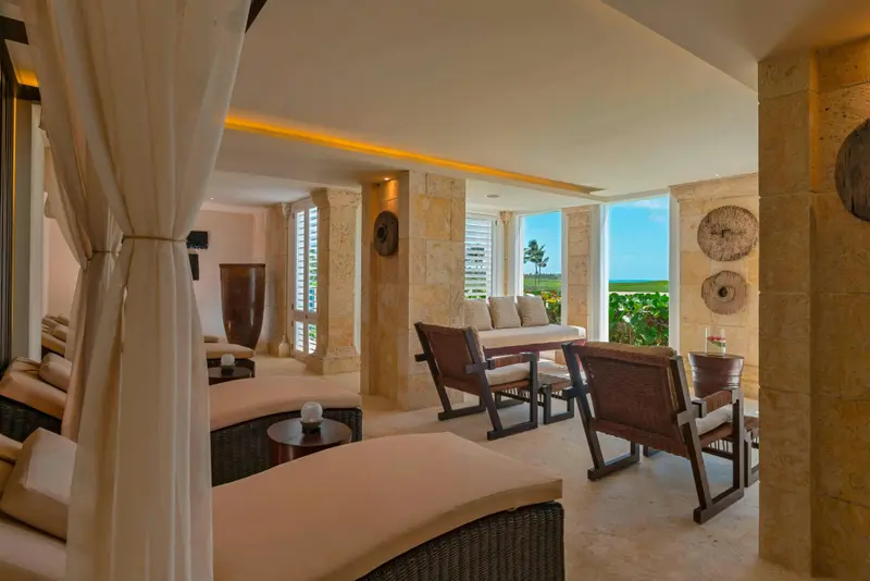 Espace de détente lumineux avec mobilier en rotin et vue sur la végétation tropicale.