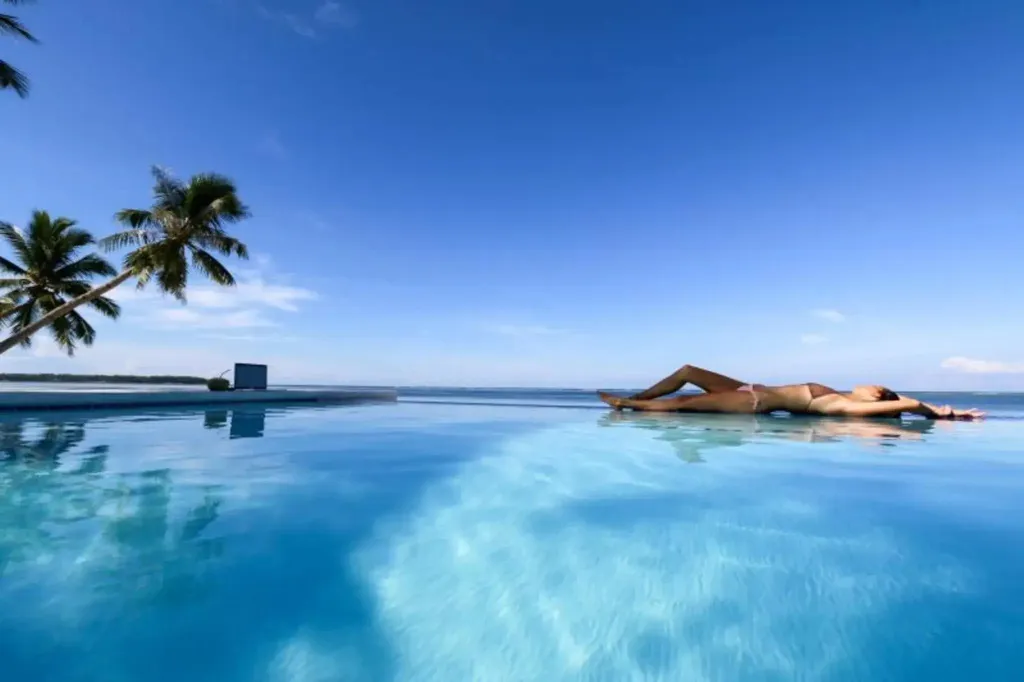 Une personne se détend dans une piscine à débordement avec vue sur la mer.