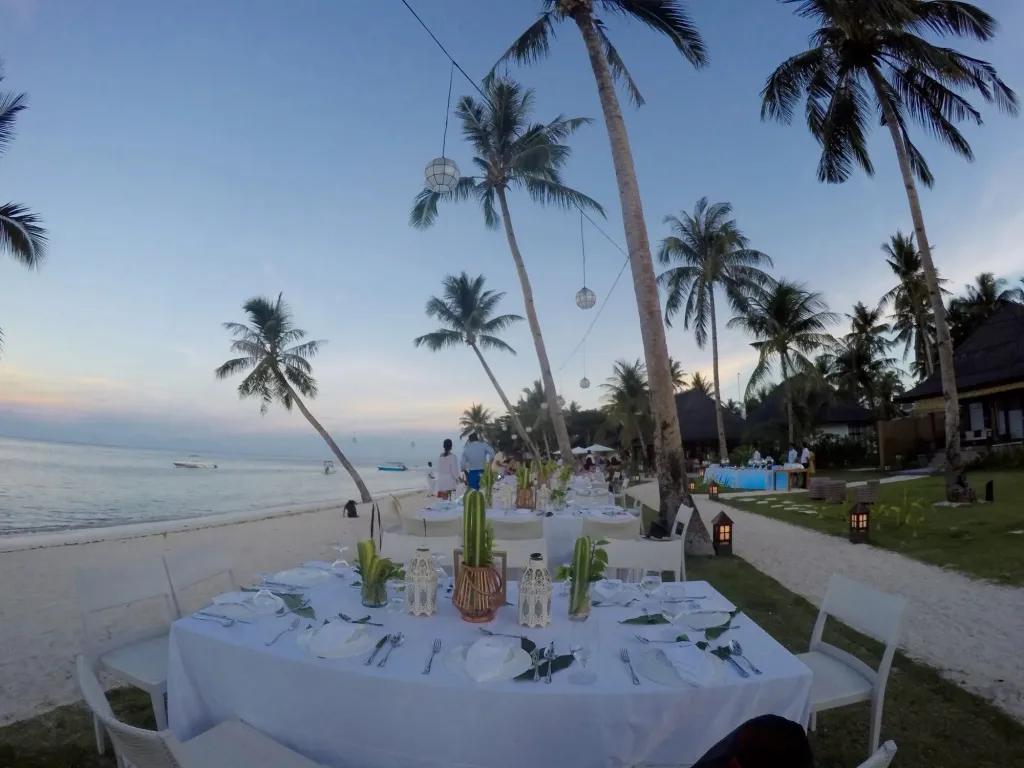 Une table dressée sur le sable blanc d'une plage au coucher du soleil.