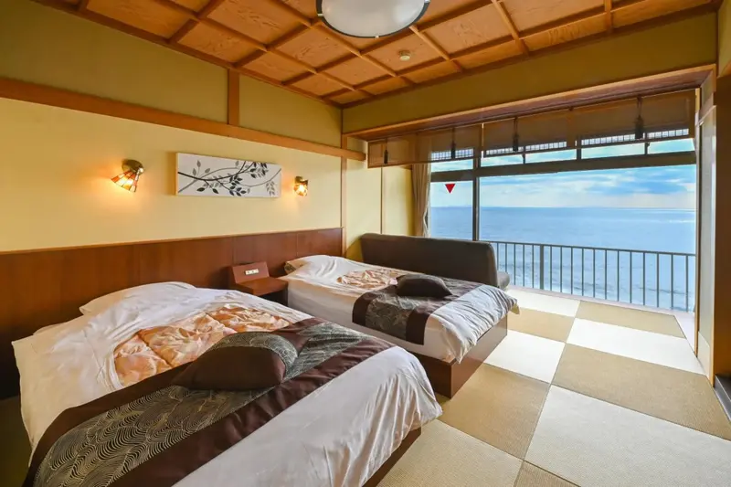 Chambre lumineuse avec deux lits et vue sur la mer.
