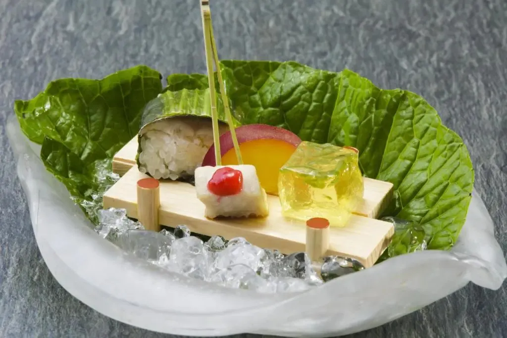 Présentation raffinée de sushis et d'une préparation à base de fruit sur un lit de glace pilée.