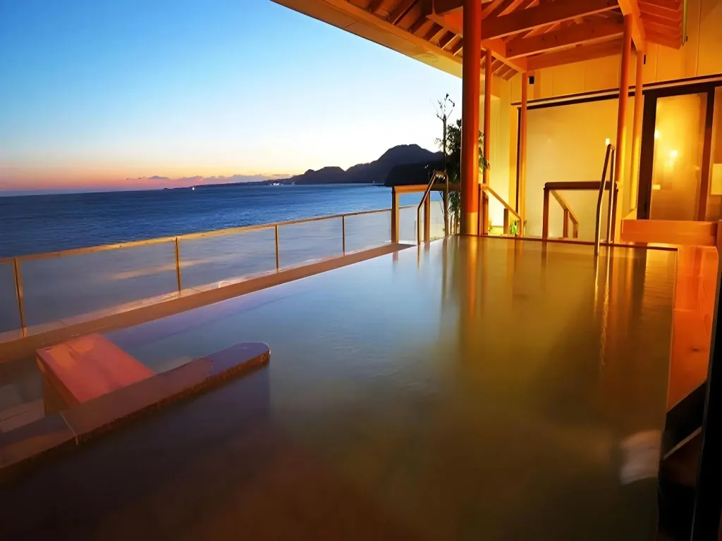 Une piscine à débordement offre une vue sur la mer au coucher du soleil.