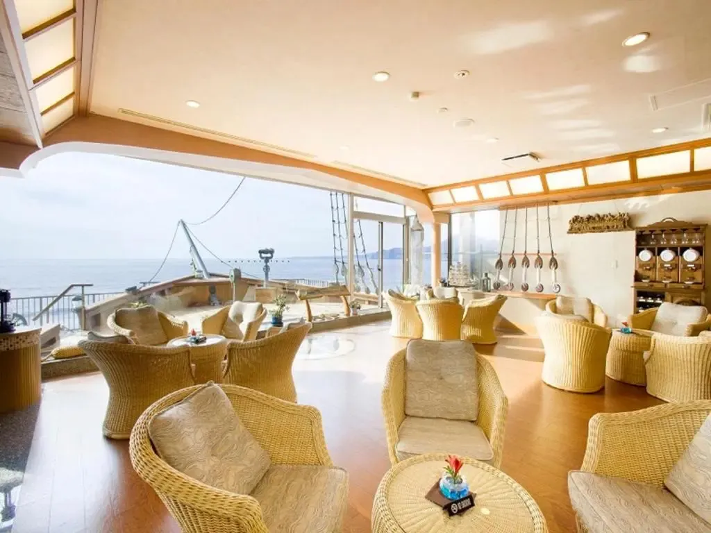 Espace de détente lumineux avec mobilier en rotin et vue sur la mer.