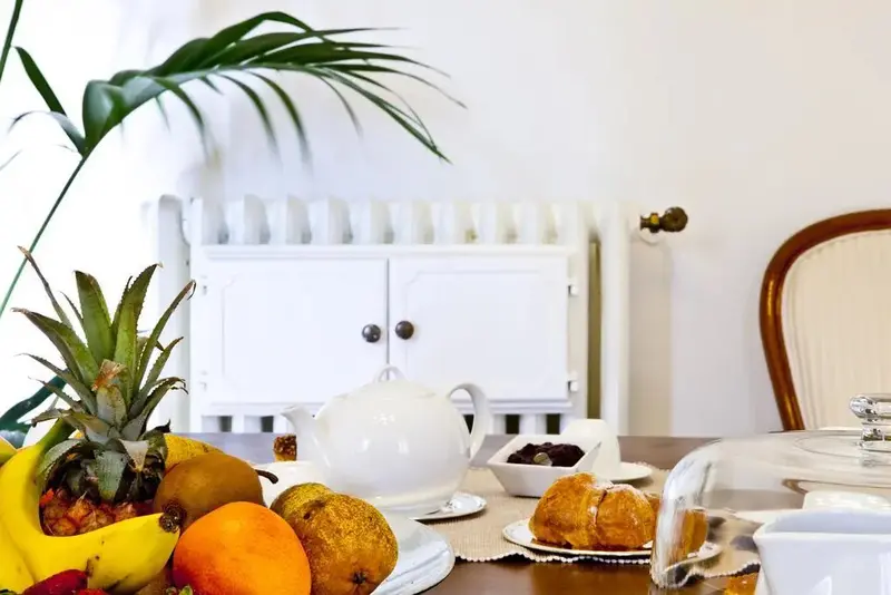 Une table en bois est dressée avec des fruits frais, une théière et de la pâtisserie.