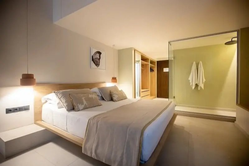 Une chambre lumineuse avec un grand lit et une douche à l'italienne.