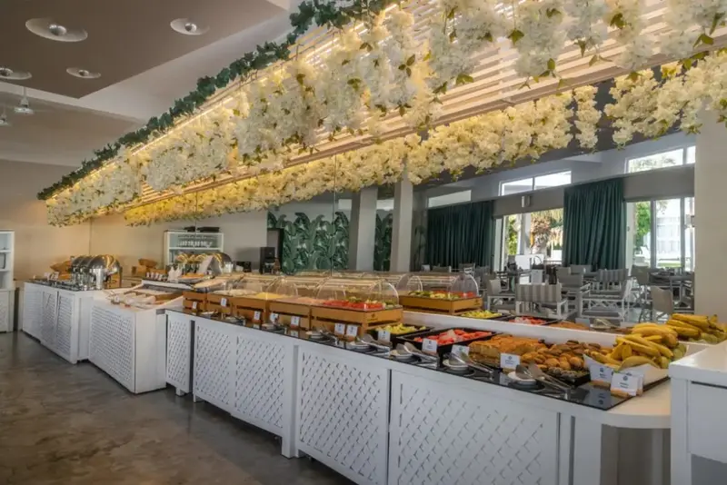 Un buffet propose une grande variété de plats et de fruits frais dans une salle lumineuse.