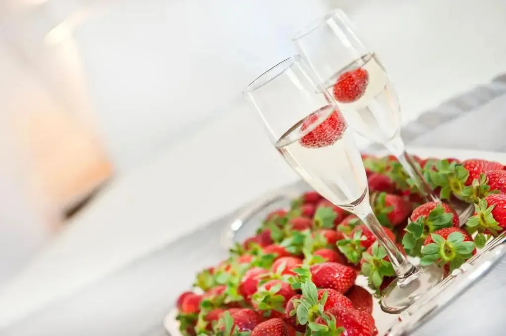 Deux coupes de champagne accompagnées de fraises fraîches sur un plateau argenté.