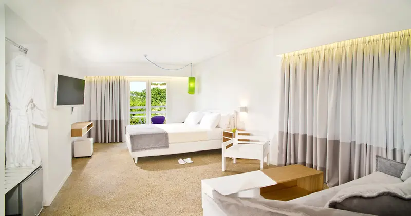 Chambre lumineuse avec un grand lit et un coin salon.