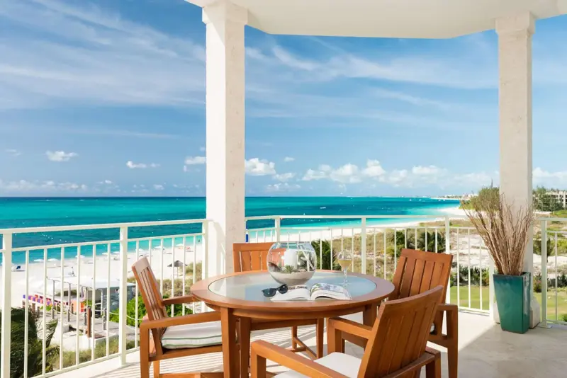 Une terrasse ensoleillée offre une vue dégagée sur la mer turquoise et la plage.