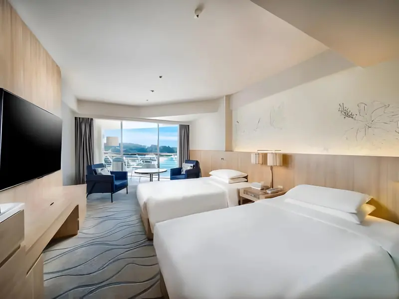 Chambre lumineuse avec deux lits simples et vue sur la mer.
