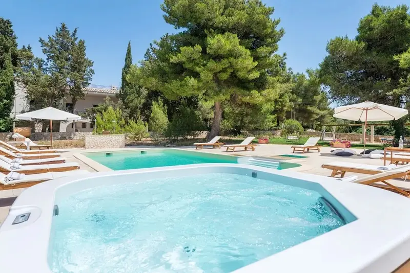 Une piscine et un jacuzzi avec des transats sous des parasols ensoleillés.