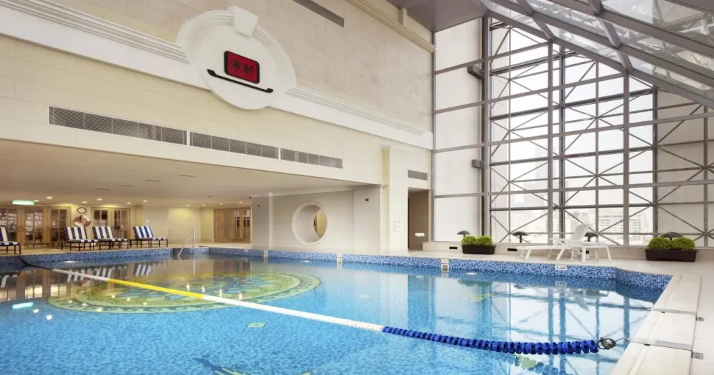 Une piscine intérieure lumineuse avec des chaises longues sur le côté.
