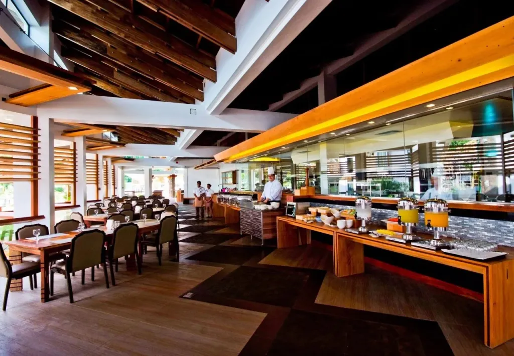 Une salle lumineuse avec des tables dressées et un buffet garni.