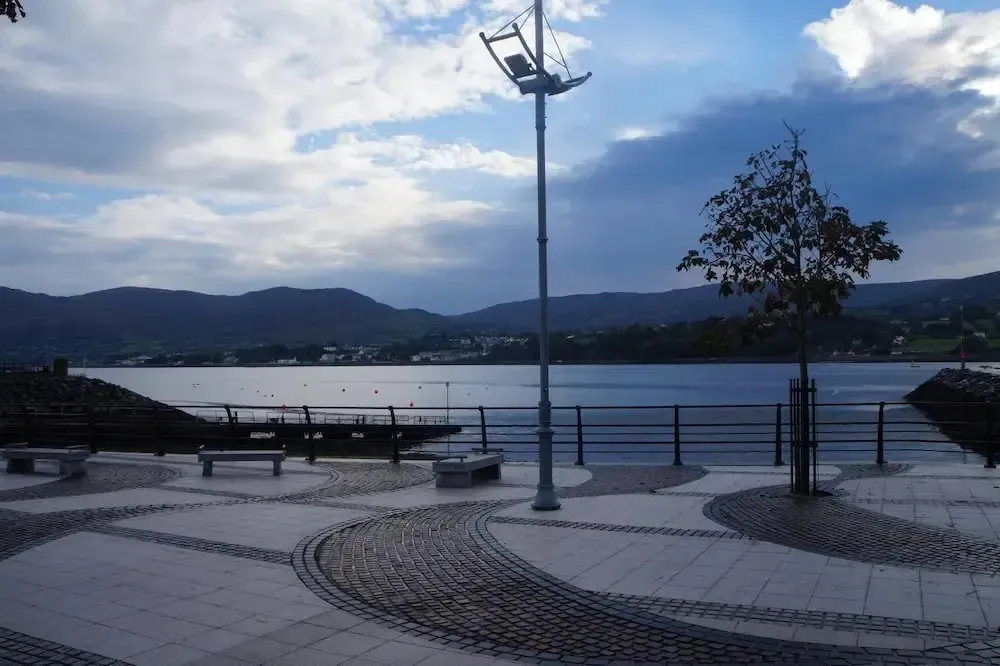 Terrasse pavée donnant sur une étendue d'eau et des montagnes en arrière-plan.