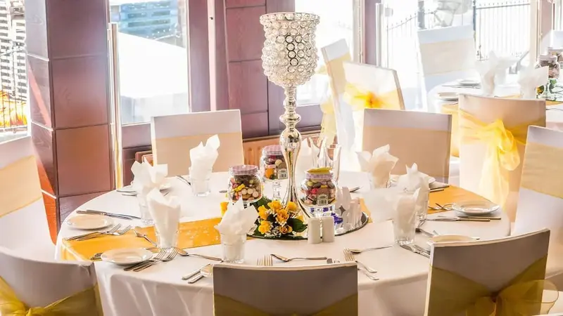 Table ronde dressée pour un repas avec une décoration florale et un chandelier.