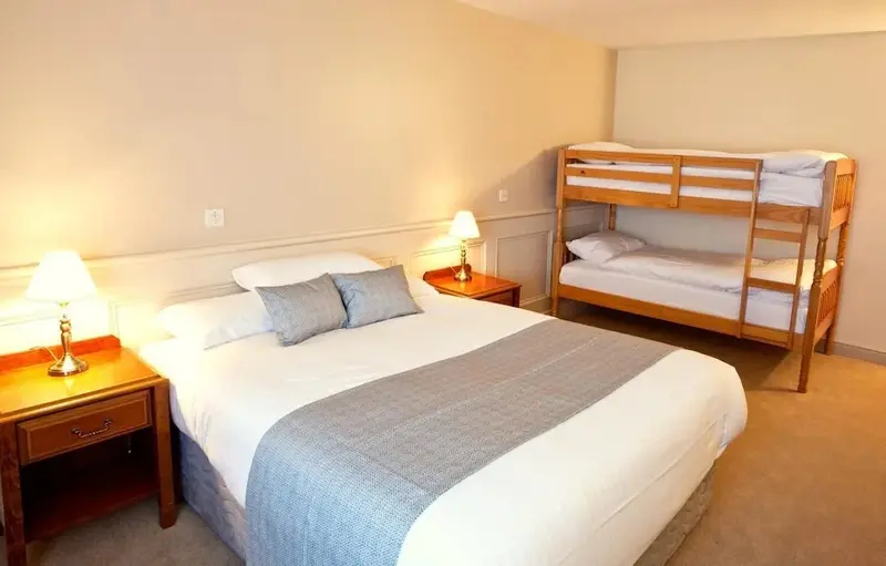 Une chambre d'hôtel lumineuse avec un lit double et un lit superposé.