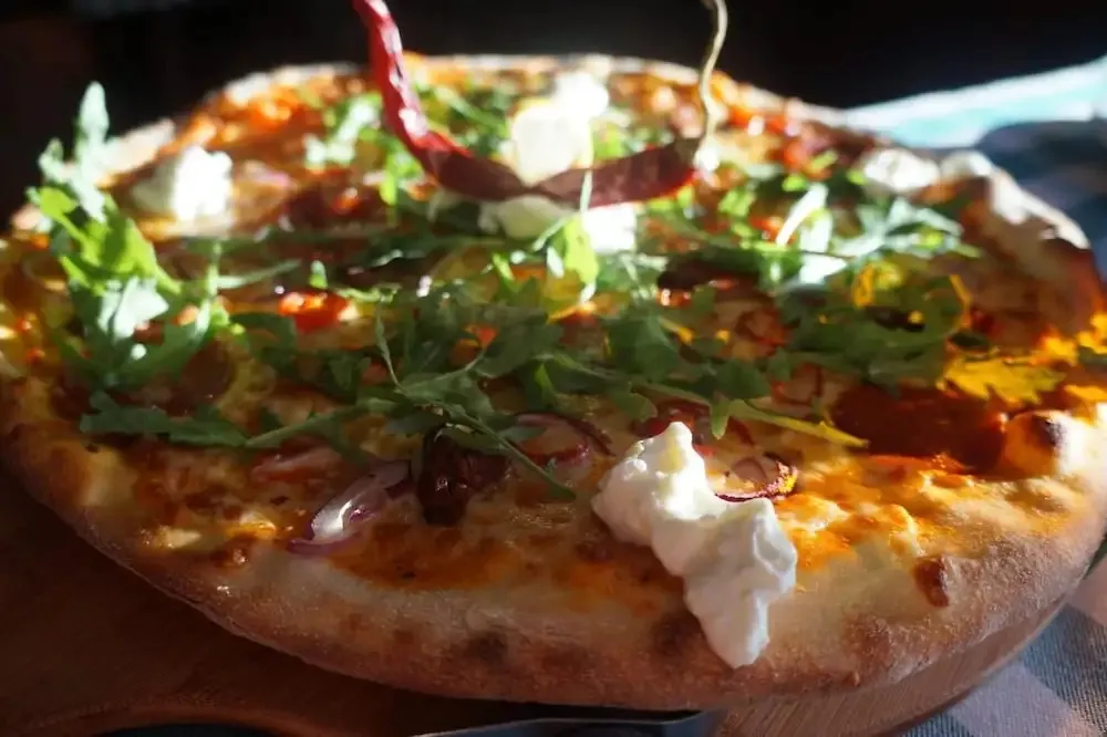 Une pizza généreusement garnie est présentée sur une planche en bois.