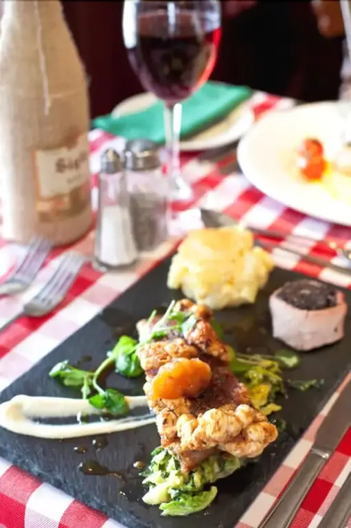 Assiette de viande accompagnée de légumes et de purée, présentée sur une ardoise.