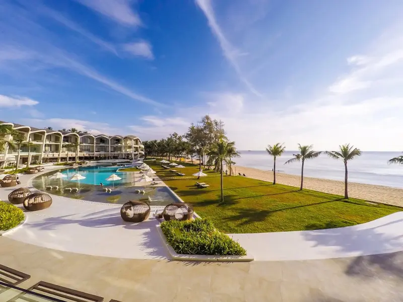 Vue aérienne d'un complexe hôtelier avec piscine et plage de sable fin.