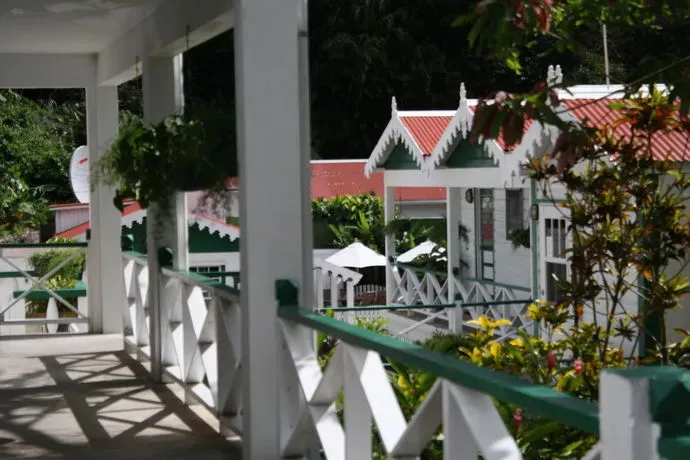 Terrasse ombragée donnant sur des bâtiments colorés dans un jardin tropical.