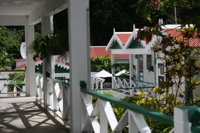 Terrasse ombragée donnant sur des bâtiments colorés dans un jardin tropical.