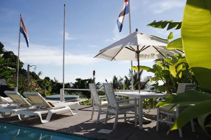 Terrasse avec mobilier de jardin et parasols près d'une piscine.