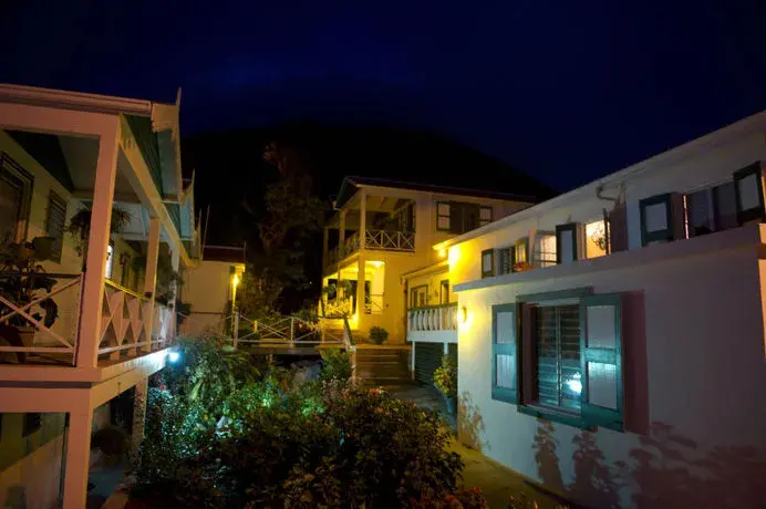 Bâtiments blancs illuminés la nuit sur une colline verdoyante.