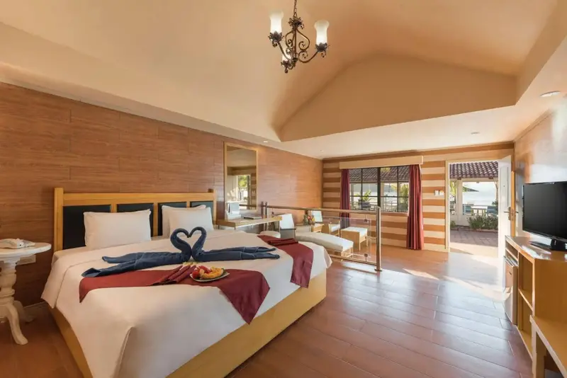 Une chambre lumineuse avec un grand lit décoré de serviettes en forme de cœur.