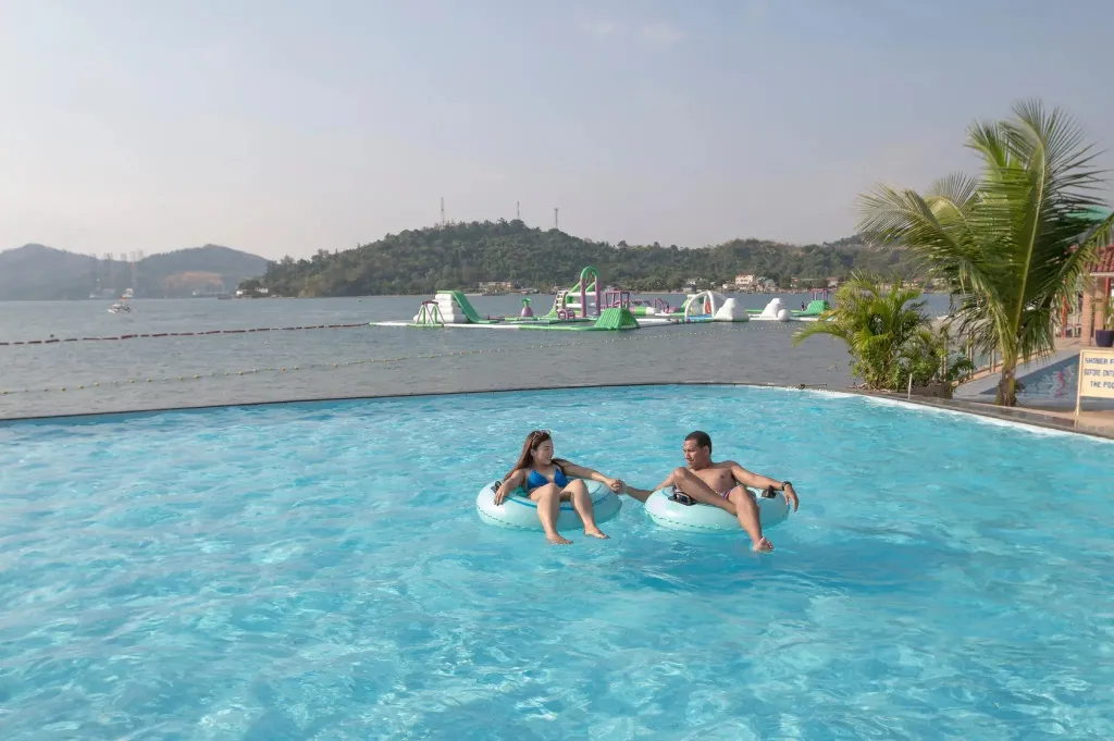 Un couple se détend sur des bouées dans une piscine en bord de mer.