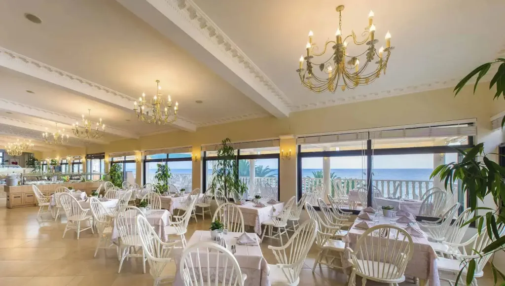 Une salle lumineuse avec des tables dressées face à une vue sur la mer.