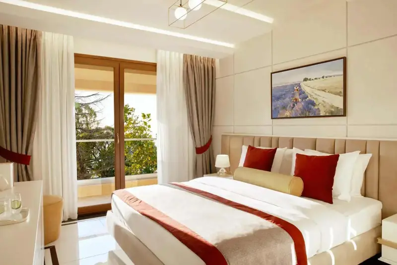 Une chambre lumineuse avec un grand lit et un accès à un balcon.