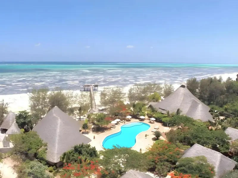 Vue aérienne d'un complexe hôtelier avec piscine et accès à la plage.