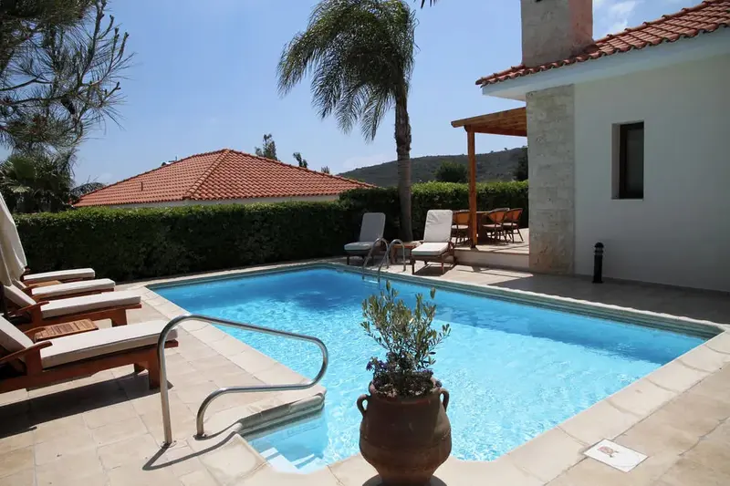 Une piscine rectangulaire avec des transats et une végétation luxuriante.