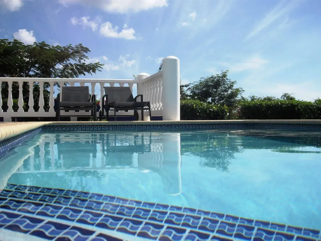 Une piscine rectangulaire avec des transats sur une terrasse ensoleillée.