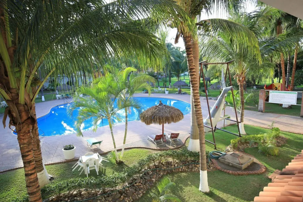 Une piscine bordée de chaises longues et de végétation tropicale.