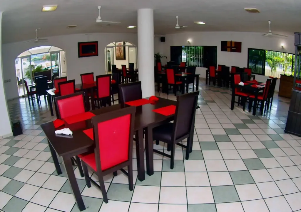 Une salle lumineuse avec des tables et des chaises rouges et noires.