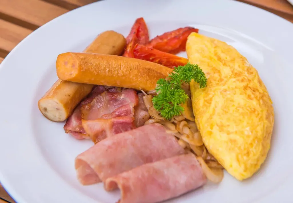Assiette copieuse avec des œufs, du bacon, des saucisses et des légumes.