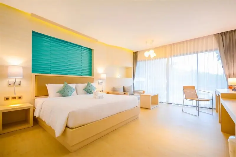 Chambre lumineuse avec un grand lit et un coin salon.