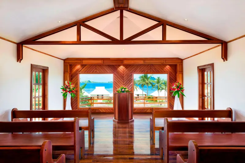 Une salle lumineuse avec des bancs en bois face à une vue sur la mer.