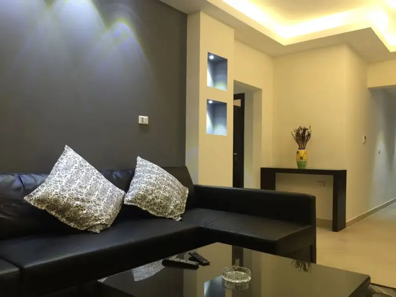 Un canapé noir avec des coussins décoratifs se trouve devant une table basse en verre.