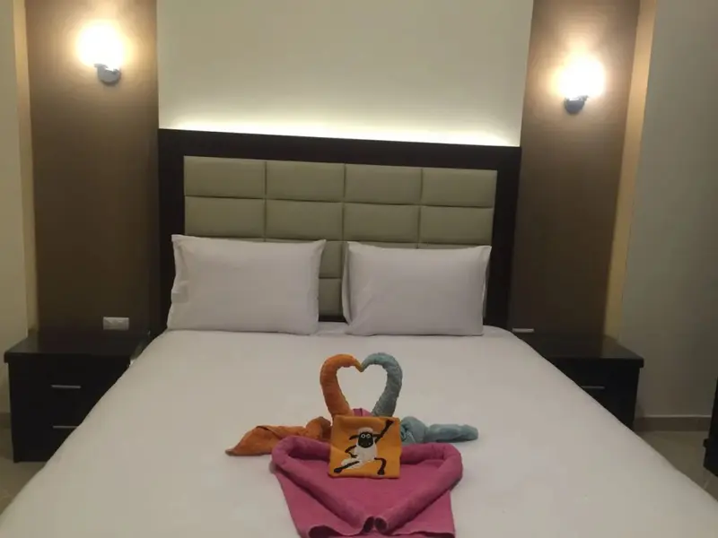 Une chambre avec un grand lit recouvert de draps blancs et décoré de serviettes en forme de cœur.