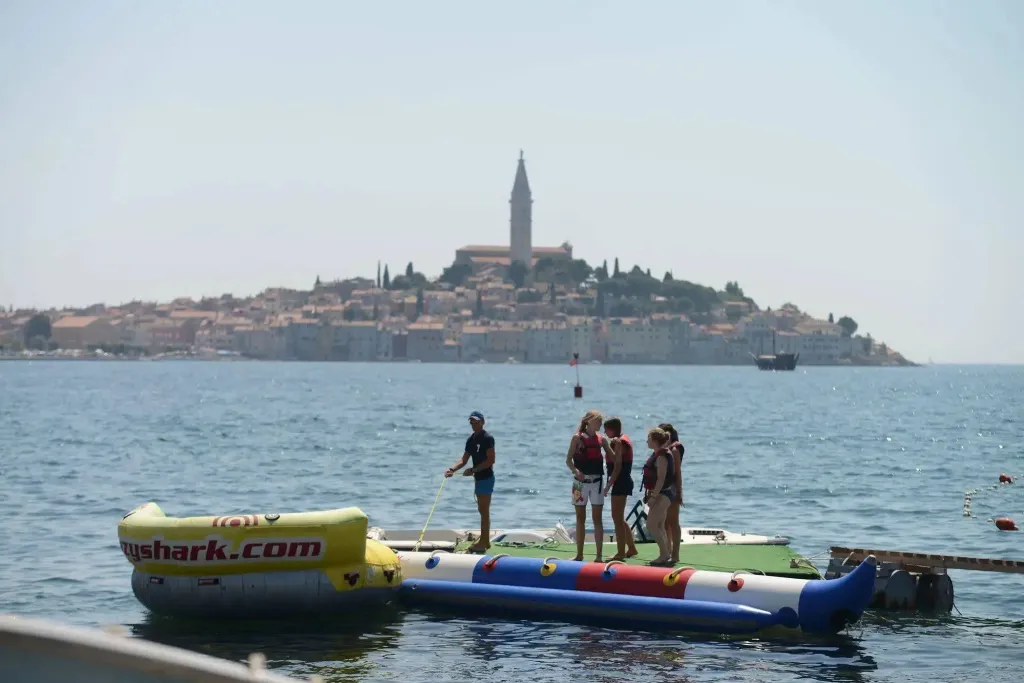 Des personnes se tiennent sur une plateforme flottante au large d'une ville côtière.