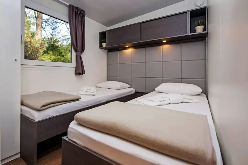Une chambre avec deux lits simples et une fenêtre.