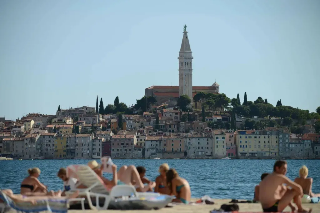 Personnes se relaxant sur une plage ensoleillée avec une ville en arrière-plan.