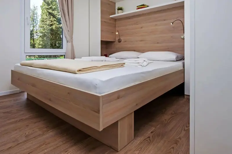 Une chambre lumineuse avec un grand lit recouvert d'une couverture et de coussins.