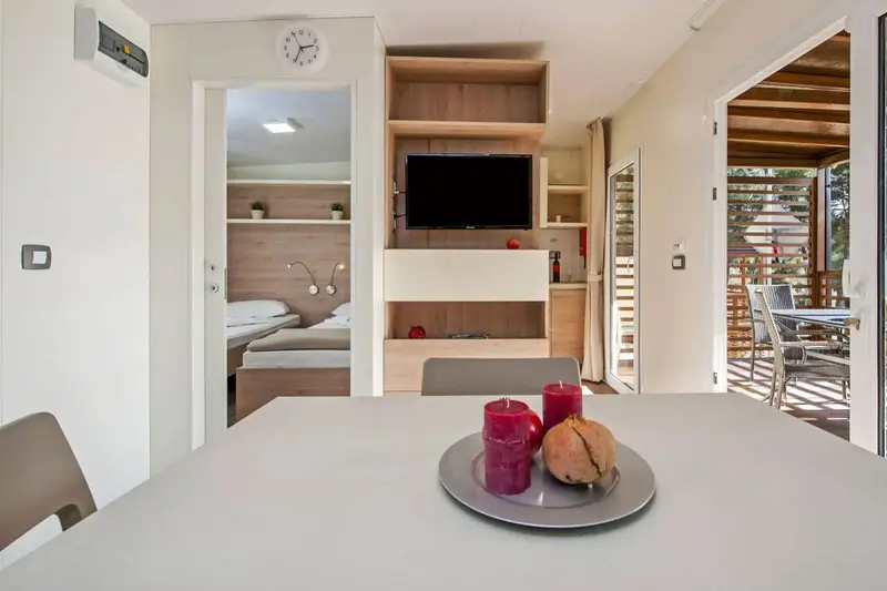 Une table est mise avec des bougies et des fruits, devant un espace de vie lumineux.