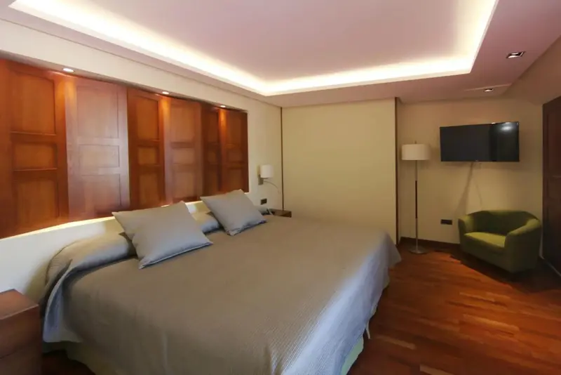 Une chambre lumineuse avec un grand lit et un fauteuil.
