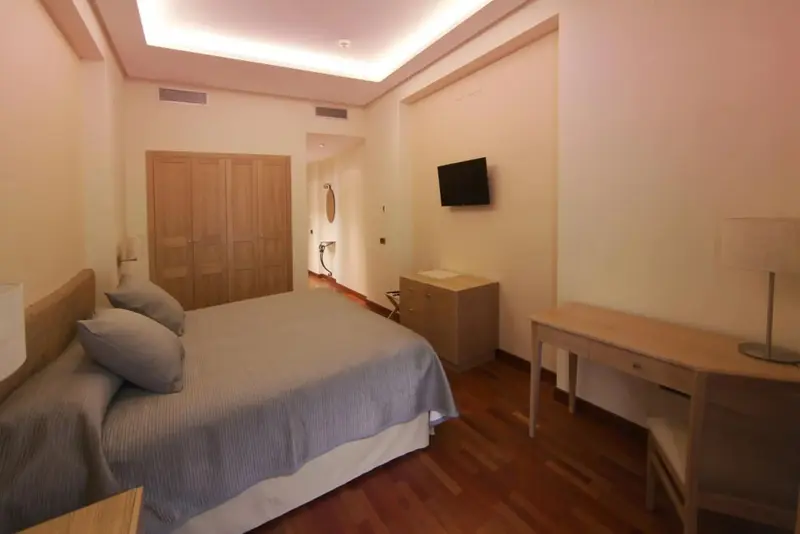 Une chambre lumineuse avec un grand lit et un bureau.