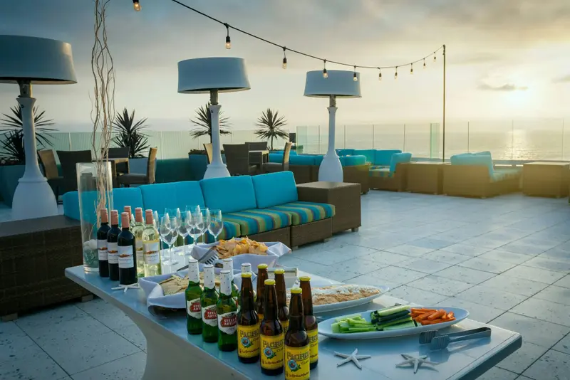 Une terrasse aménagée avec des canapés et une table garnie de boissons et de collations.