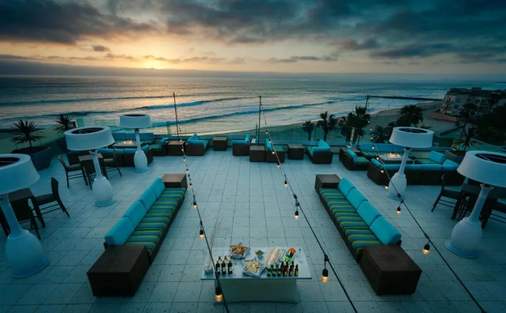 Terrasse aménagée avec des salons et une vue sur la mer au coucher du soleil.